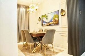 Enjoy meals in this elegant dining area with a round table and six chairs, surrounded by a beautiful tropical landscape painting.