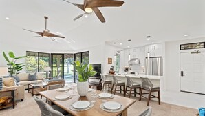 A modern kitchen with white cabinets, stainless steel appliances, and a dining area with a wooden table set for four. - NEWLY REMODELED-QUIET LOCATION-AC-WELL EQUIPPED-METICULOUS CLEANING (Wailea)