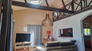 Ein Wohnzimmer mit Fernseher, einer Couch und einem Essbereich mit Tisch und Stühlen.