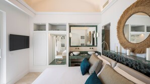 A modern bedroom with a large bed, a vanity with a mirror, and a television mounted on the wall.