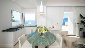 A modern kitchen with a large window, a dining table with chairs, and a vase of flowers.