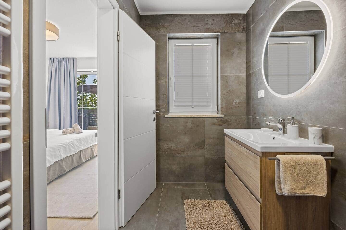 A modern bathroom with a shower, a sink, and a mirror.