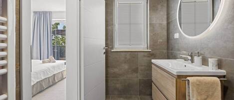 A modern bathroom with a shower, a sink, and a mirror.