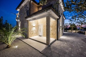 Une maison moderne avec une façade en pierre, un patio couvert et une antenne parabolique.