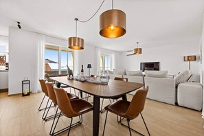 A modern living room with a dining area, a sofa set, and a TV.