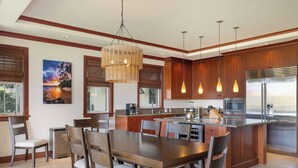 A modern kitchen with wooden cabinets, a large island, stainless steel appliances, and pendant lighting. - Kolea 2E -Newly furnished in 2024 3 BR Condo -Hilton Waikoloa Access Included (Waikoloa)