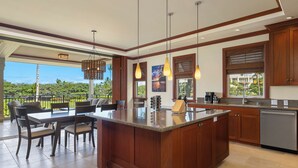 A spacious kitchen with a central island, wooden cabinets, and a view of the outdoors. - Kolea 2E -Newly furnished in 2024 3 BR Condo -Hilton Waikoloa Access Included (Waikoloa)