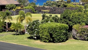 A well-maintained garden with a variety of shrubs and trees, a lawn, and a view of the ocean. - Kolea 2E -Newly furnished in 2024 3 BR Condo -Hilton Waikoloa Access Included (Waikoloa)