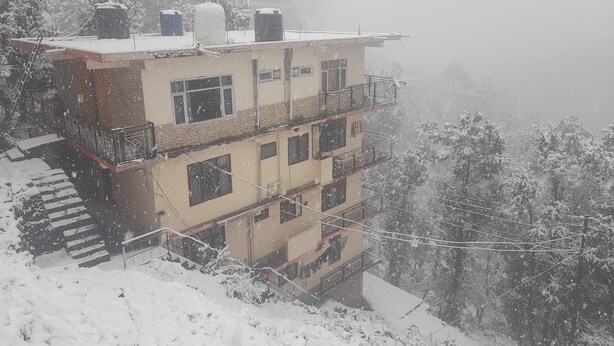 A multi-story building with balconies and a staircase leading to the entrance. - Love Kush Cottage  (Taradevi)