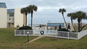 A coastal hotel with a white fence, palm trees, and a view of the ocean. - Tradewinds 151 1 Bedroom Condo (St. Augustine)