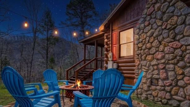 A stone cabin with a fire pit and blue chairs in front. - Greenbrier Woods 2 Bedroom Cabin (Gatlinburg)