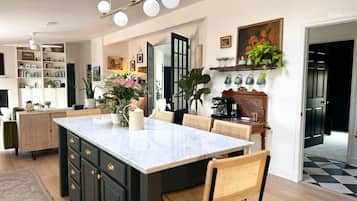 A modern kitchen with a large island, built-in cabinets, and a coffee station.