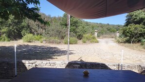 An outdoor table with a stone wall and a view of a dirt path leading through a wooded area. - Quiet house for rent (Saint-Marcel-d'Ardèche)