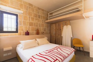 Een slaapkamer met een bed, een raam, een stoel, een kledingkast en een stapelbed.