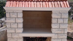 A stone-built outdoor oven with a tiled roof, surrounded by rocks and vegetation. - Perfect Getaway Near Korčulas Scenic Sights and Beaches (Korcula)