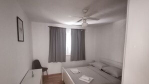 A small, single-bed room with a desk and chair, a ceiling fan, and a window with curtains. - Perfect Getaway Near Korčulas Scenic Sights and Beaches (Korcula)