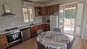 A modern kitchen with a gas stove, dishwasher, and a refrigerator. There is a dining table with a tablecloth featuring city names. - Perfect Getaway Near Korčulas Scenic Sights and Beaches (Korcula)