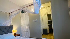 Ein Schlafzimmer mit einem großen Bett, einem Nachttisch mit Lampe, einem Kleiderschrank und einem Deckenventilator.