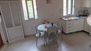 A compact kitchen with a dining area, featuring a small table with chairs, a window, and a door.
