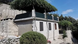 A stone building with a green roof, a small porch, and a stone wall.