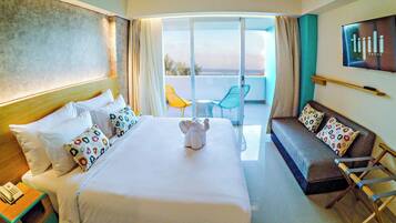Habitación de hotel con cama, sofá, televisión y balcón con sillas.
