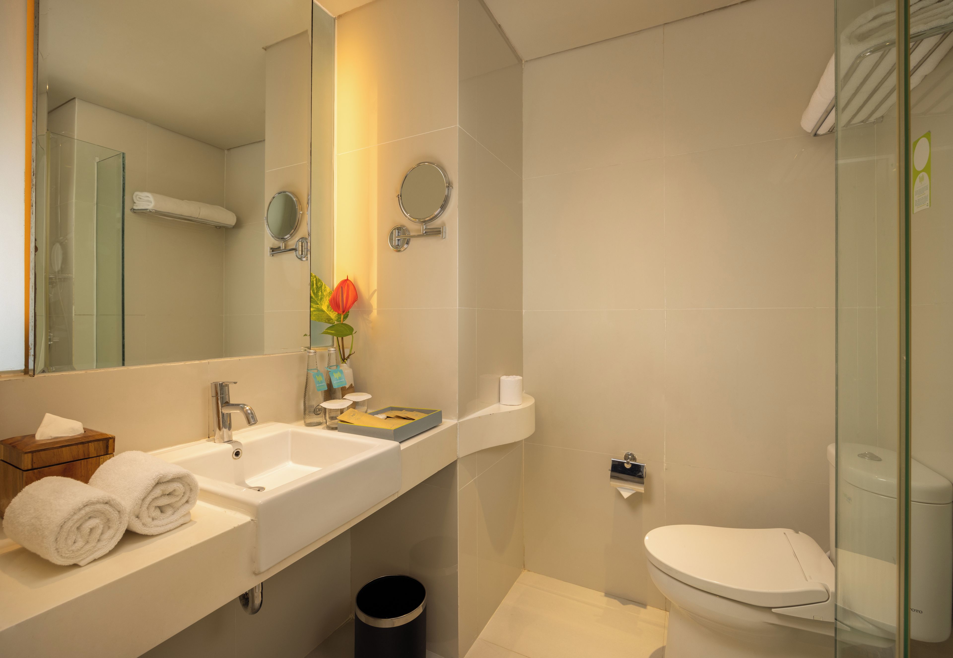 Ein modernes Badezimmer mit einem weißen Waschbecken, Spiegel und WC.