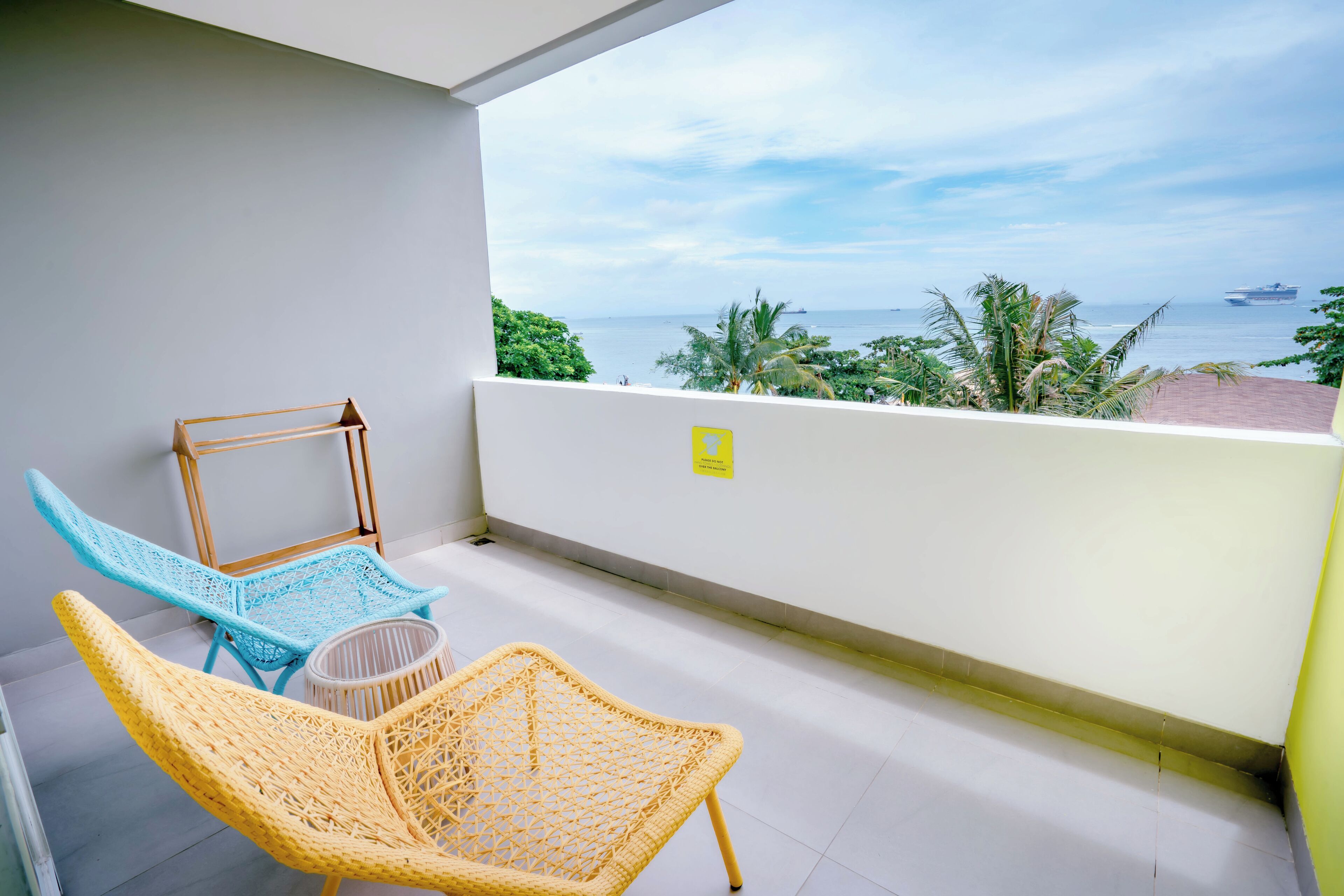 A balcony with wicker chairs, a small table, and a view of the sea.