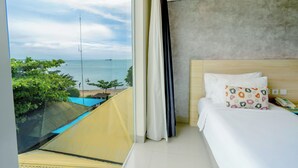 Une chambre d’hôtel avec un lit, une vue sur la mer et un balcon donnant sur la mer et sur un bateau.