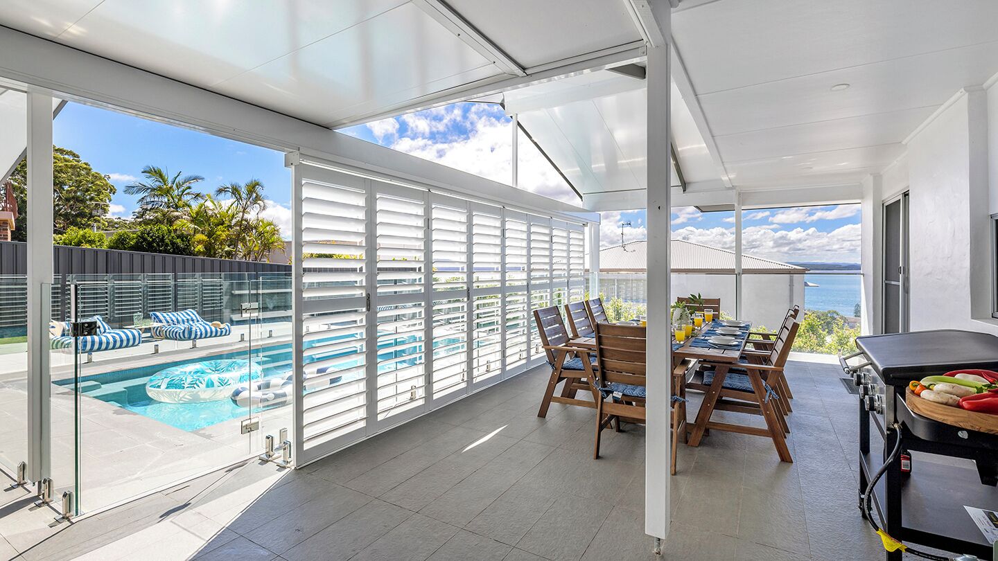 A modern outdoor dining area with a view of a pool and ocean.