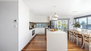Uma cozinha moderna com armários brancos, uma ilha central e uma área de refeições com cadeiras de madeira.