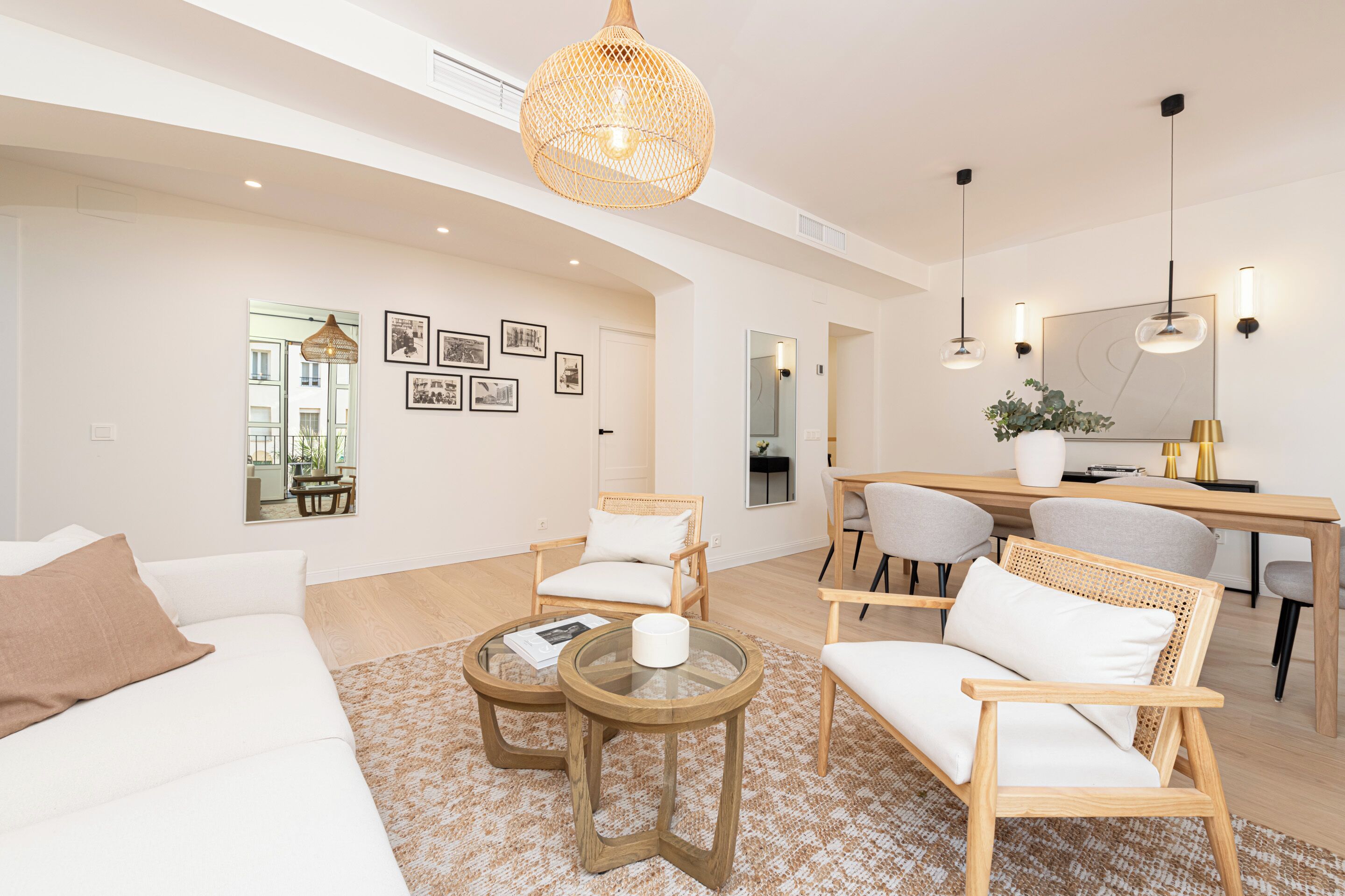 Una sala moderna con un sofá, dos sillones, una mesa de centro y un comedor con una mesa y sillas.