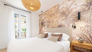 A bedroom with a large bed, a wooden nightstand, a wall-mounted lamp, and a window with curtains. - Solaga - Gutenberg Beach (Málaga)