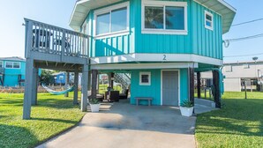 A two-story house with a balcony and a covered porch. - Adorable Port Aransas beach cottage with community pool and outdoor spaces.  Clo (Port Aransas)