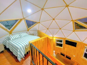 A room with a geometric ceiling design, a bed with striped bedding, and a wooden table. - Domos Frutillar  (Frutillar)