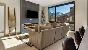Una sala de estar moderna con chimenea, un sofá grande y un comedor con sillas.