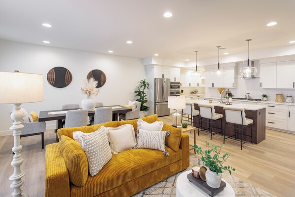 A modern kitchen with white cabinets, a stainless steel refrigerator, and a central island with bar stools.