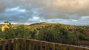 Blick auf einen Hügel mit Häusern und einem Holzzaun im Vordergrund.