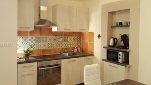 A compact kitchen with light wooden cabinets, a tiled backsplash, and a built-in microwave.