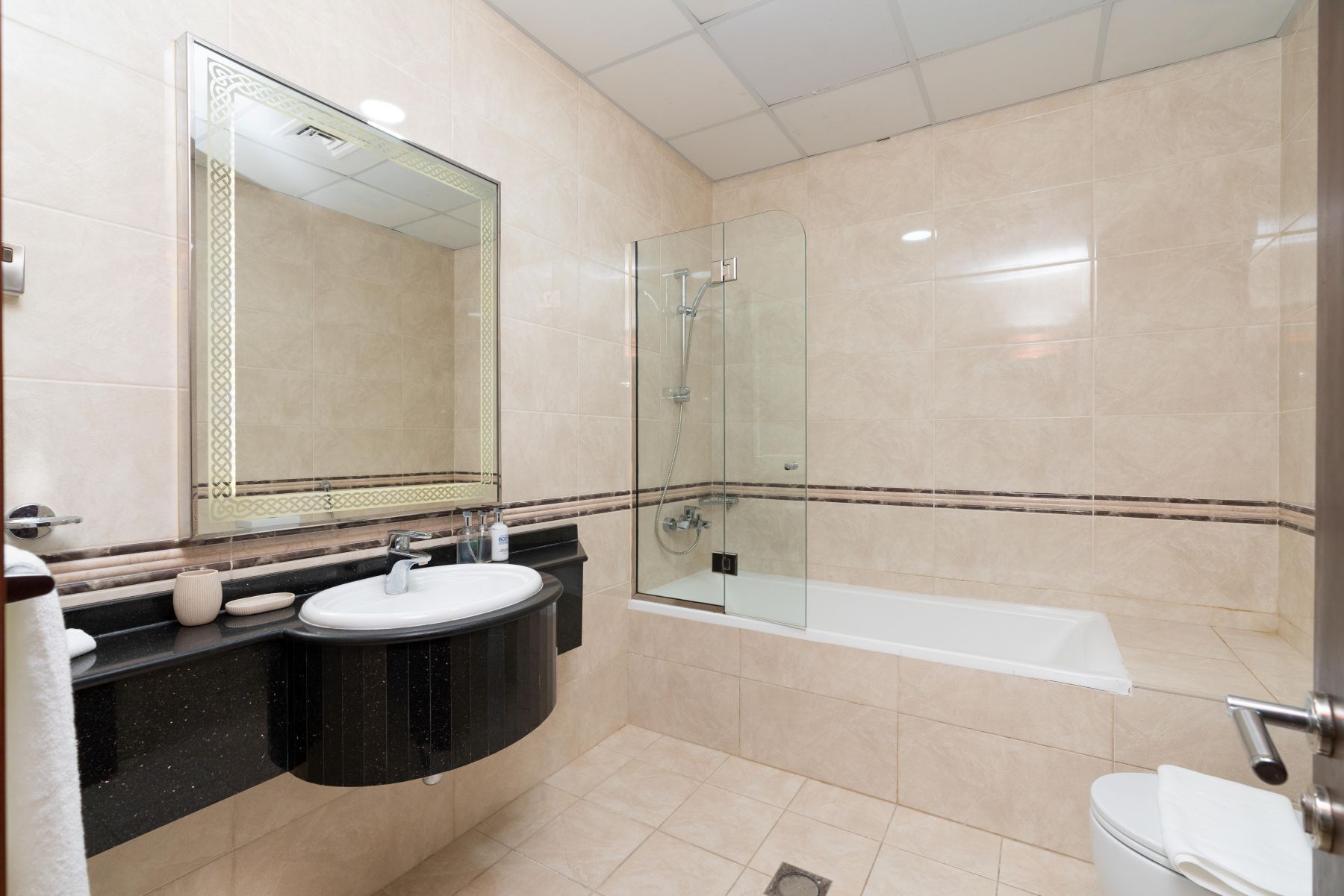 A modern bathroom with a glass-enclosed shower, a white sink, and a bathtub.