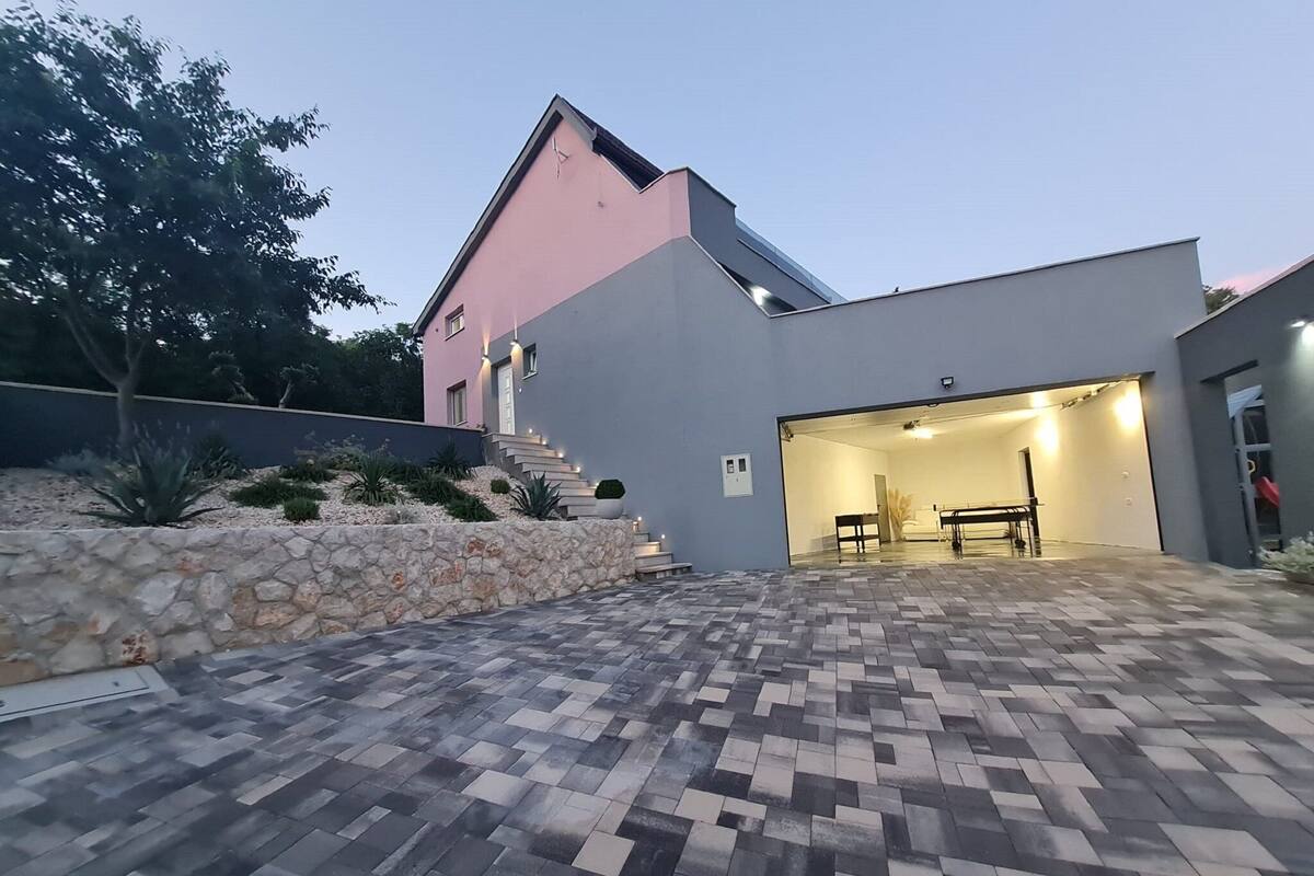 Una casa moderna con pared de piedra y patio empedrado.