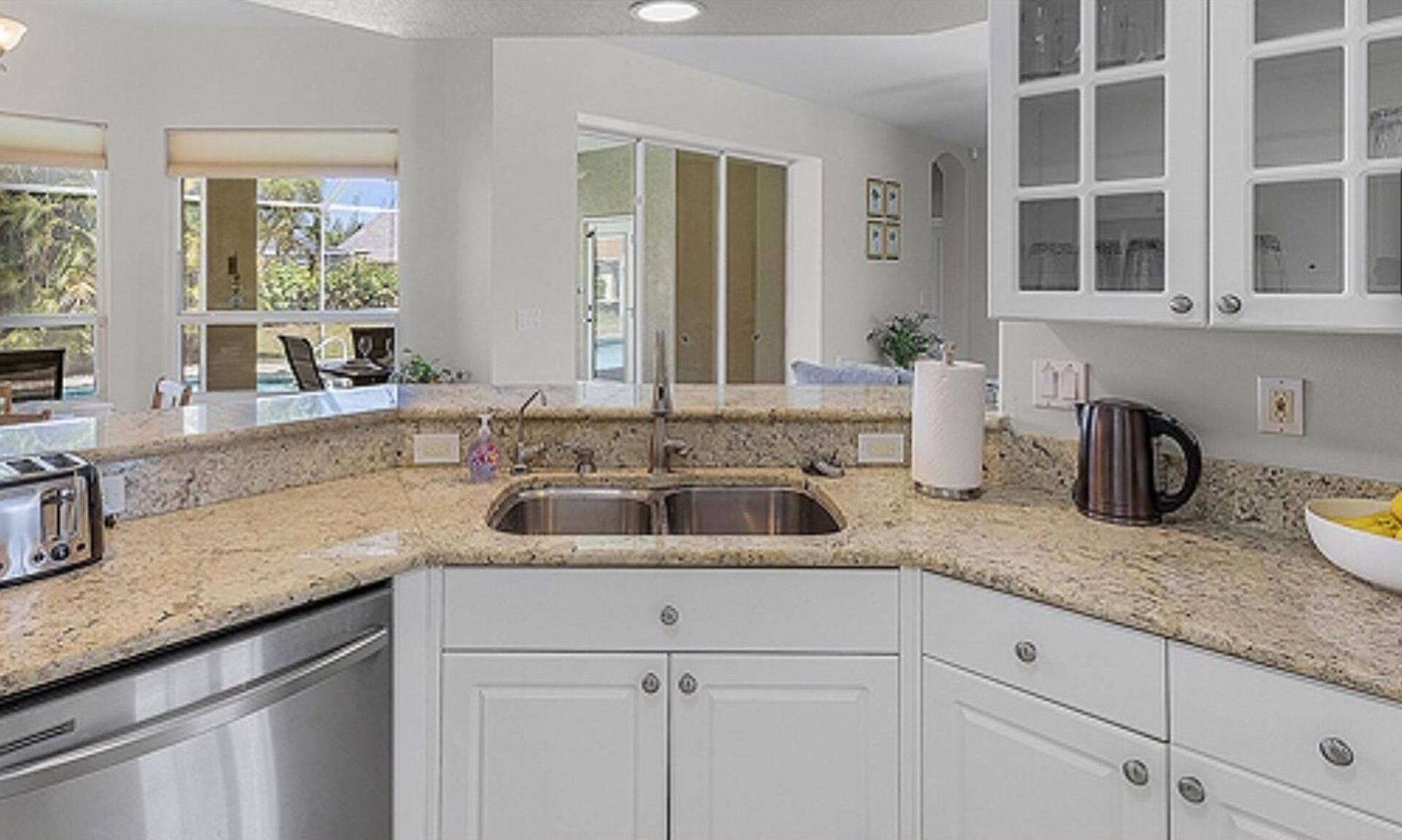 A kitchen with granite countertops, stainless steel appliances, and white cabinetry.