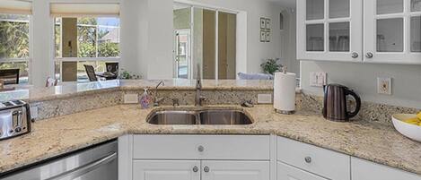 A kitchen with granite countertops, stainless steel appliances, and white cabinetry.