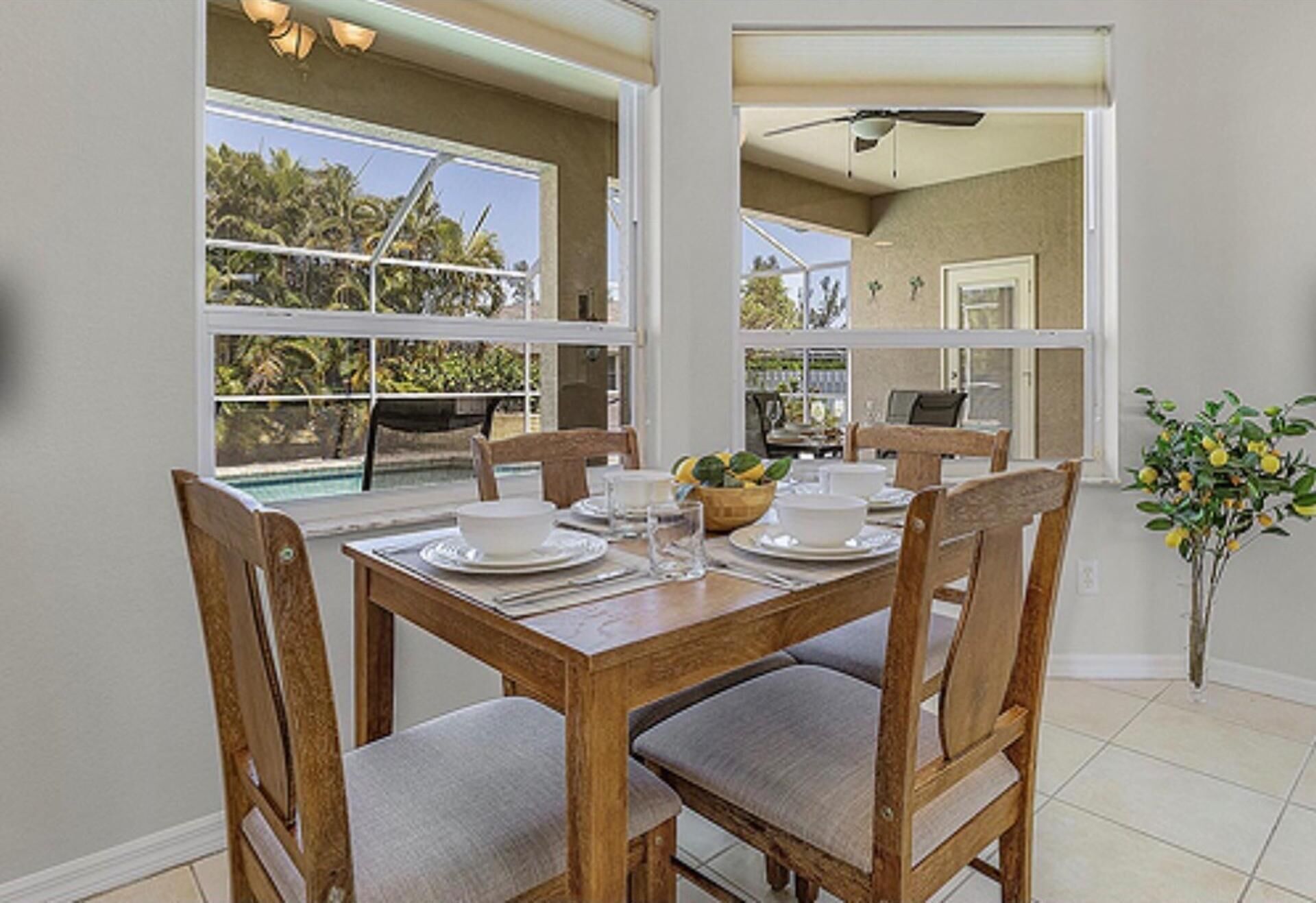 A dining area with a wooden table set for four, surrounded by chairs with cushioned seats.