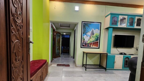 A hallway with a wooden bench, a painting, and a TV on a cabinet. - Holiday Home - GF 3BHK Full House (Madurai)