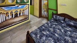 A bedroom with a bed, a ceiling fan, a green door, and a wall with a mural. - Holiday Home - GF 3BHK Full House (Madurai)