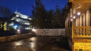 A stone-walled courtyard with a wooden structure featuring ornate metalwork. - Mihman Konak Hotel (Kars)