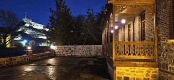 Un patio con paredes de piedra y una estructura de madera con detalles de metal ornamentado.