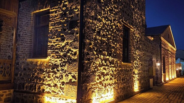 A narrow cobblestone street at night with illuminated stone buildings. - Mihman Konak Hotel (Kars)