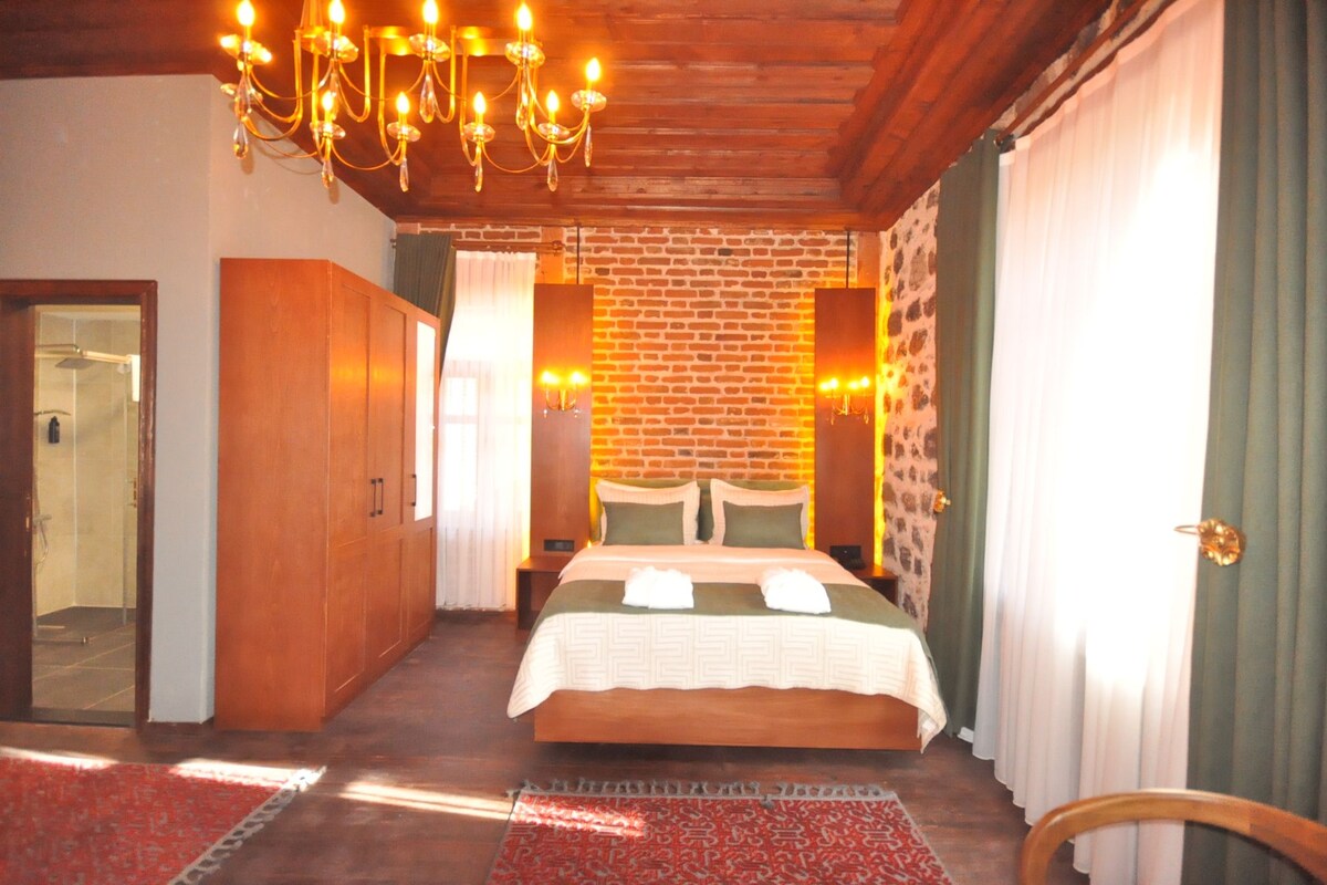 A bedroom with a brick wall, wooden ceiling, and a chandelier.