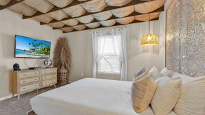 A bedroom with a large bed, a television on the wall, a dresser, and a decorative wall panel. - Unique, 7 bed Luxury Disney Escape, Theater & Heated Pool (Davenport)